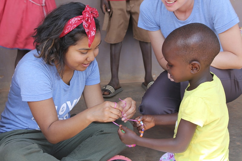 18 C4L Uganda 0406 Web An intern give a child a Gospel Bracelet