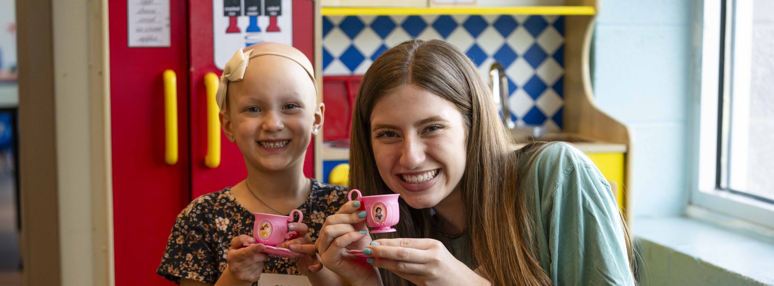 A volunteer and little girl are having fun playing tea party at a respite event.