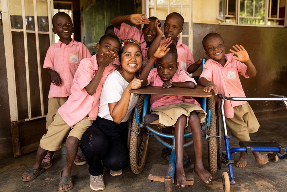 An intern poses for a photo with children