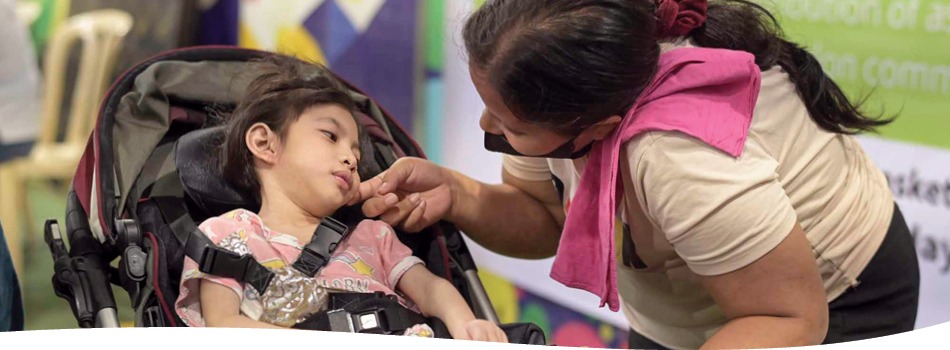 A mother touches her daughter's cheek as she sits in her wheelchair.