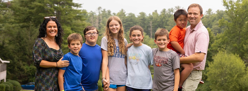 A family with six kids of various ages, some with disabilities, smiles for the camera. They are enjoying their time at Family Retreat.