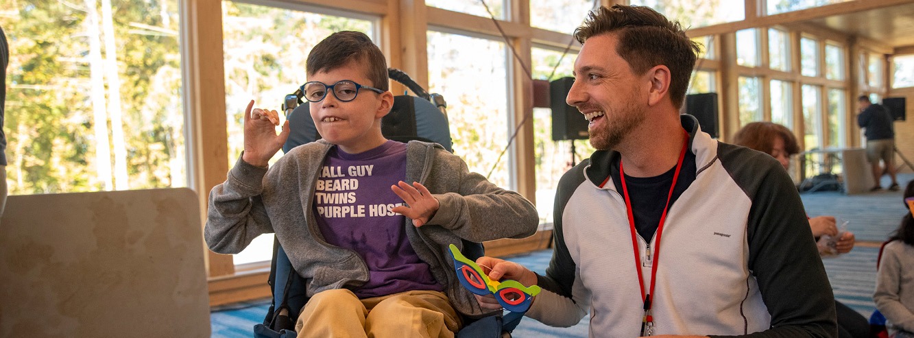 A child in a wheelchair and his volunteer buddy are hanging out at Family Retreat.