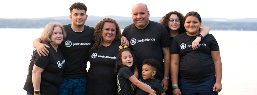 A group of people posing for a photo in front of a body of water.